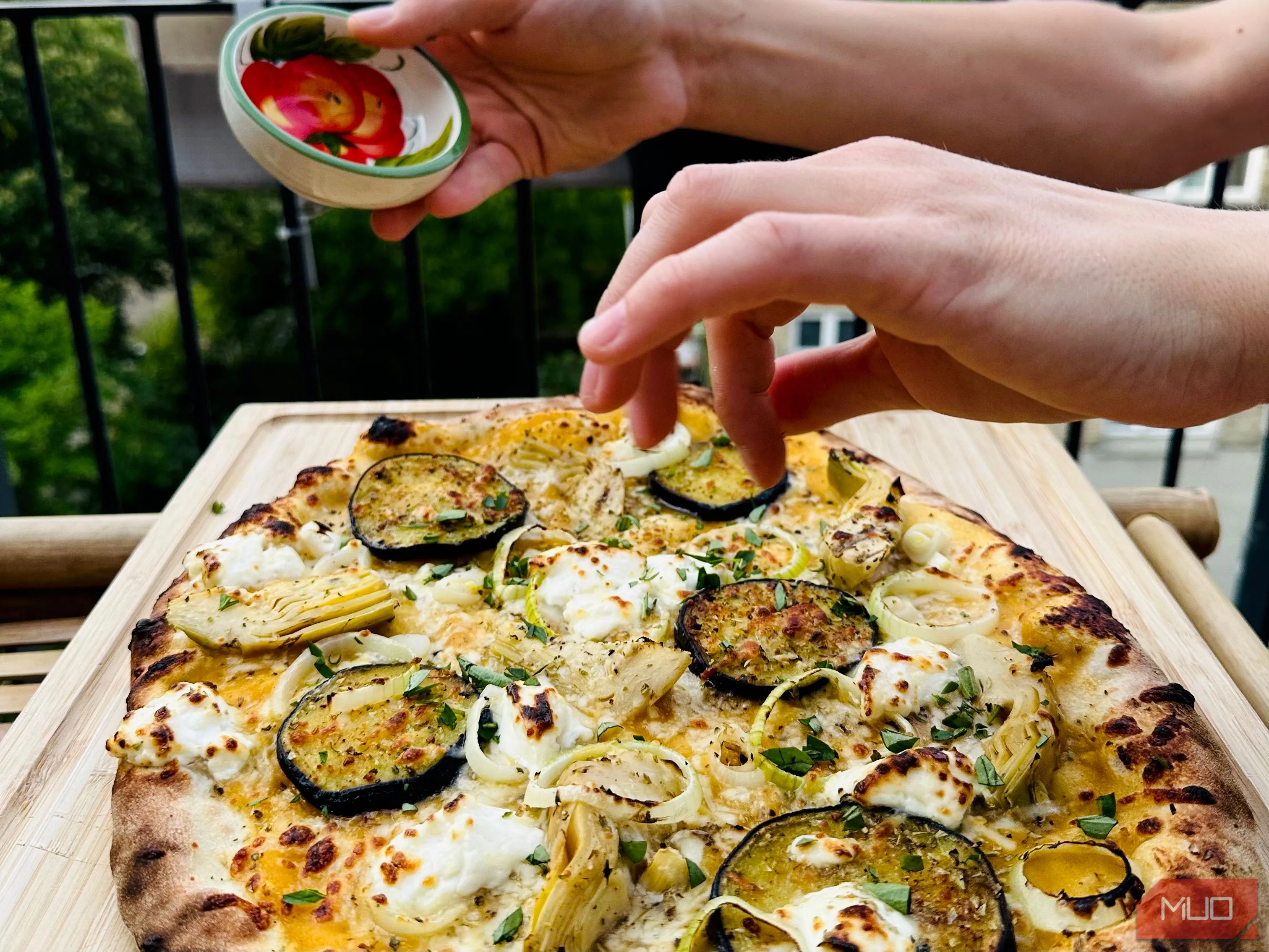 Bàn tay đang cắt lát pizza nóng hổi vừa ra lò tại nhà, thể hiện khoảnh khắc ẩm thực và giải trí trong nhiếp ảnh đời thường.