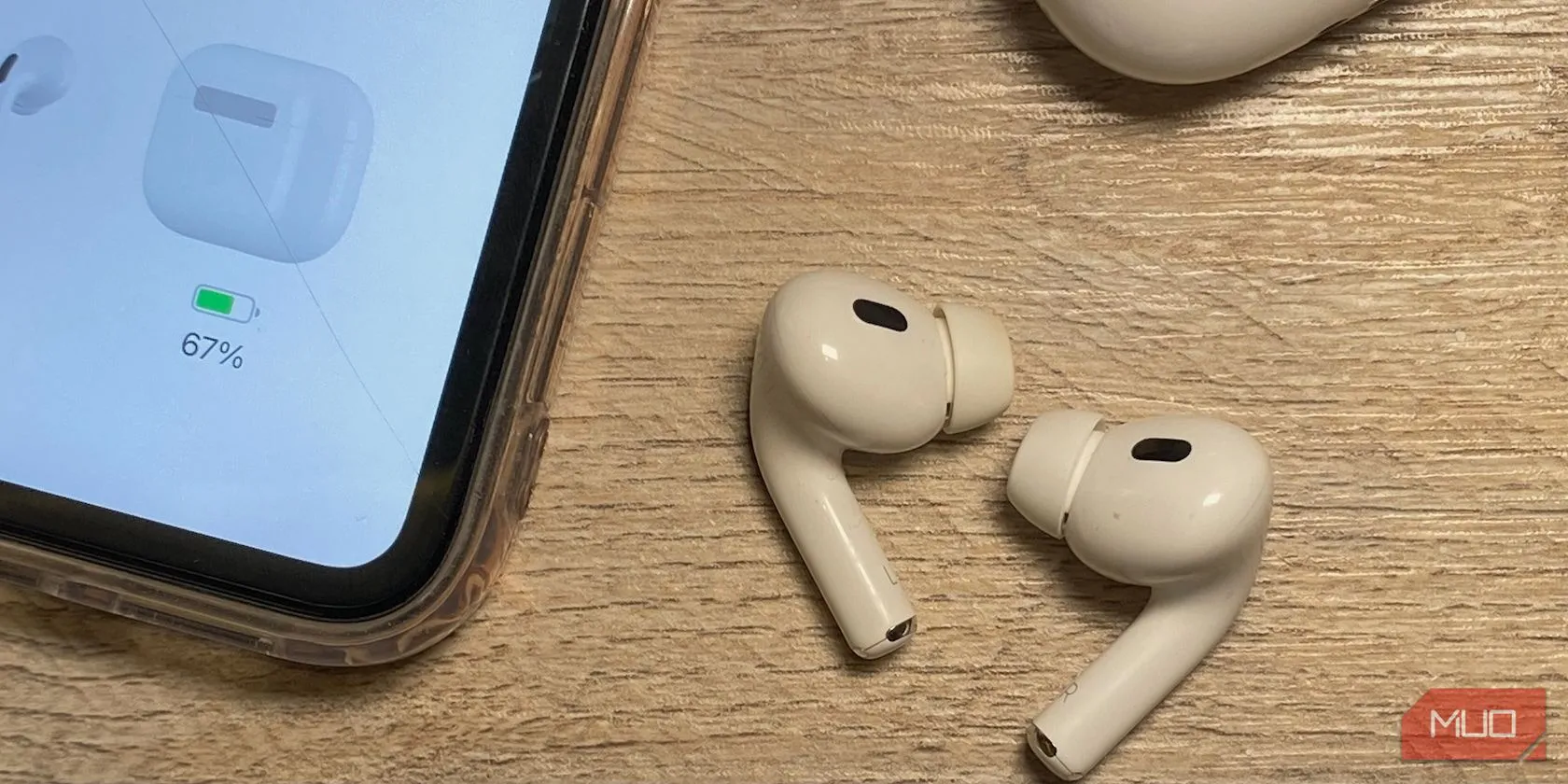 Các thế hệ tai nghe AirPods in-ear đặt cạnh iPhone trên bàn gỗ, minh họa sự khác biệt về chiều dài thân tai nghe