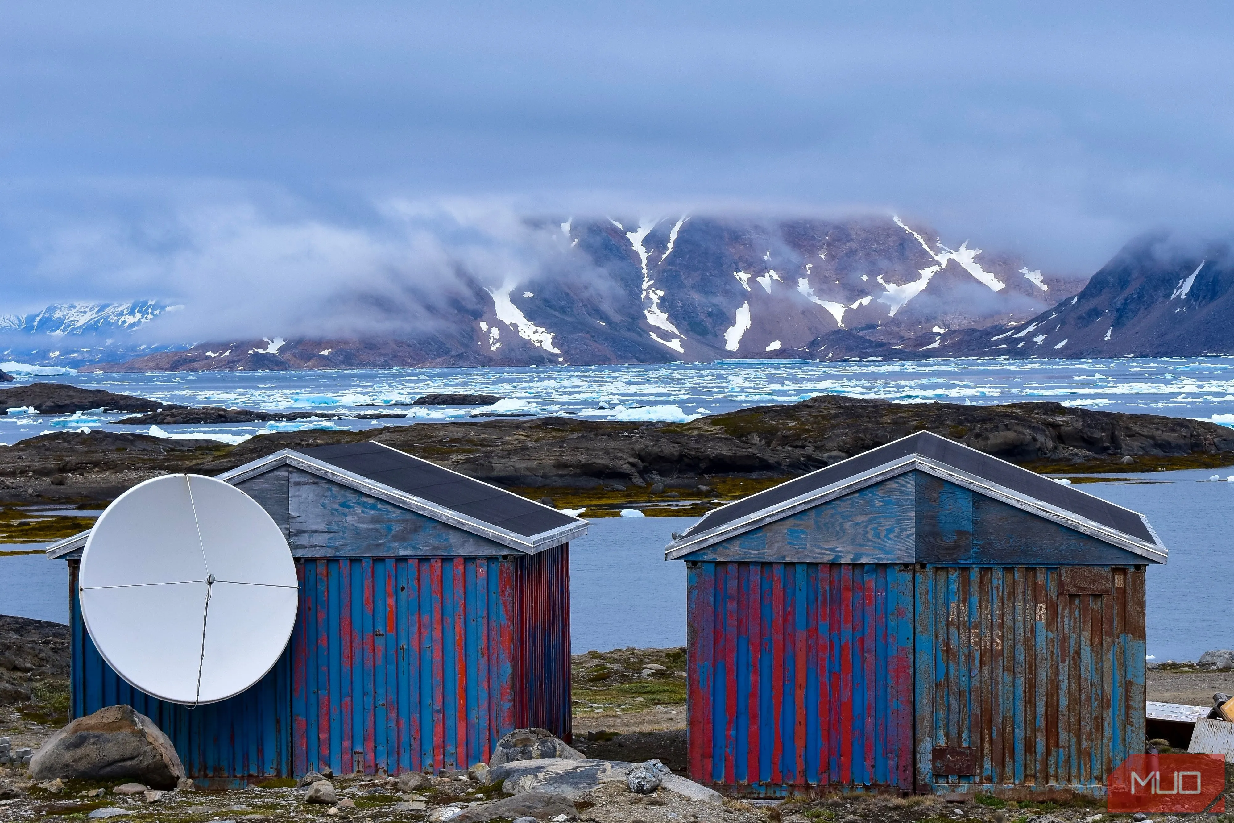 Cận cảnh những ngôi nhà gỗ nhiều màu sắc trước núi và băng trôi ở Greenland.