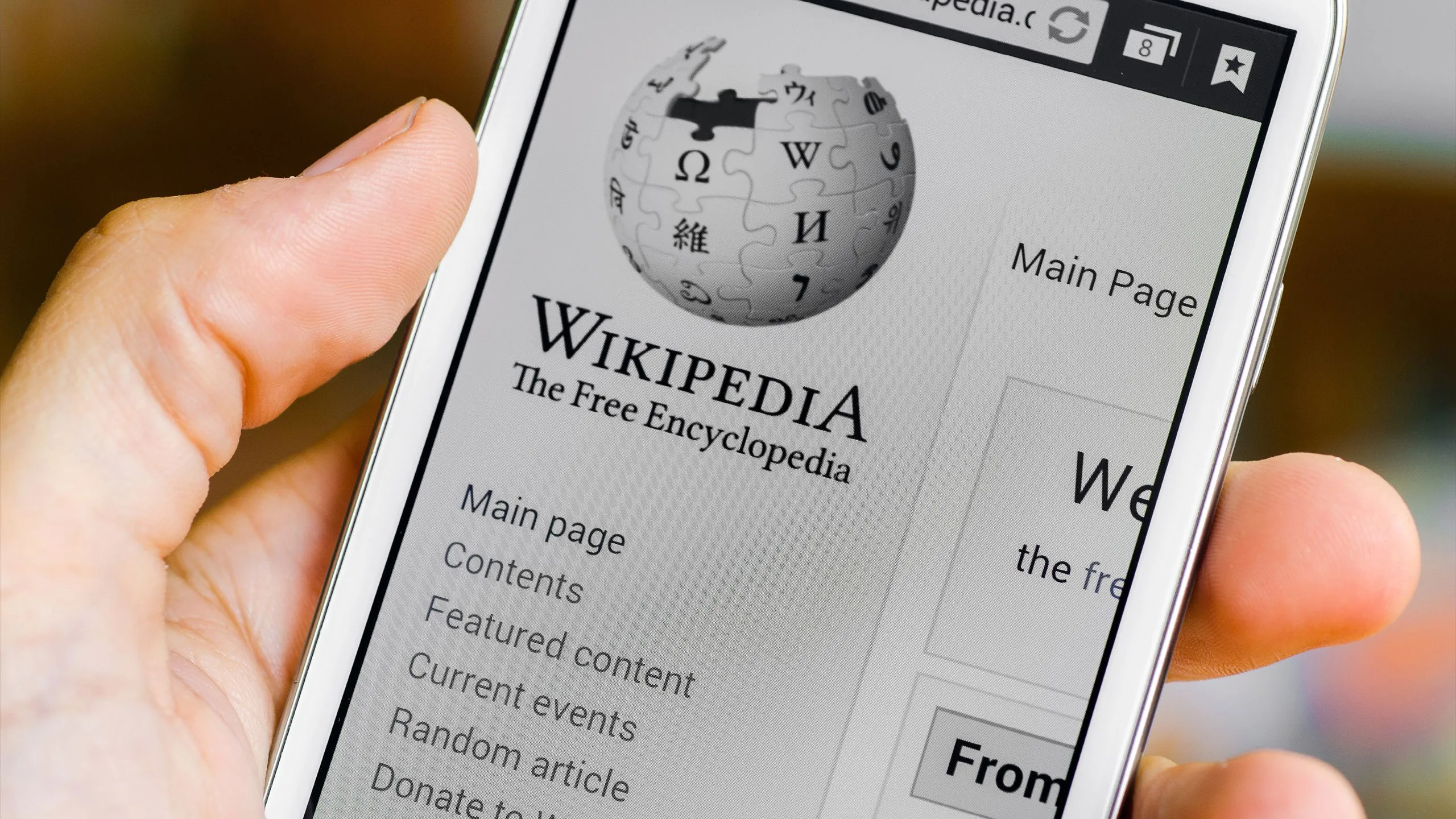 Điện thoại hiển thị ứng dụng Wikipedia đang mở, tượng trưng cho việc tra cứu thông tin và sự hỗ trợ của AI trong việc quản lý nội dung.