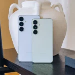 Điện thoại Samsung Galaxy S25 và S25+ màu xanh lá, xanh dương đặt cạnh giá sách.