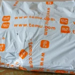Gói hàng Temu trên bàn gỗ, minh họa sự thay đổi chi phí vận chuyển