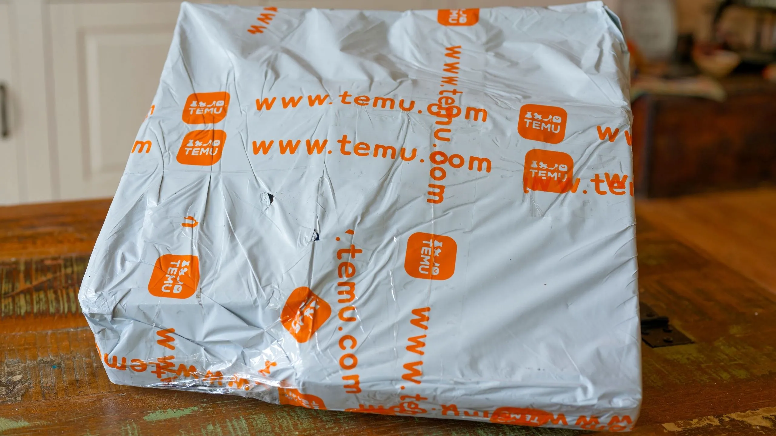 Gói hàng Temu trên bàn gỗ, minh họa sự thay đổi chi phí vận chuyển