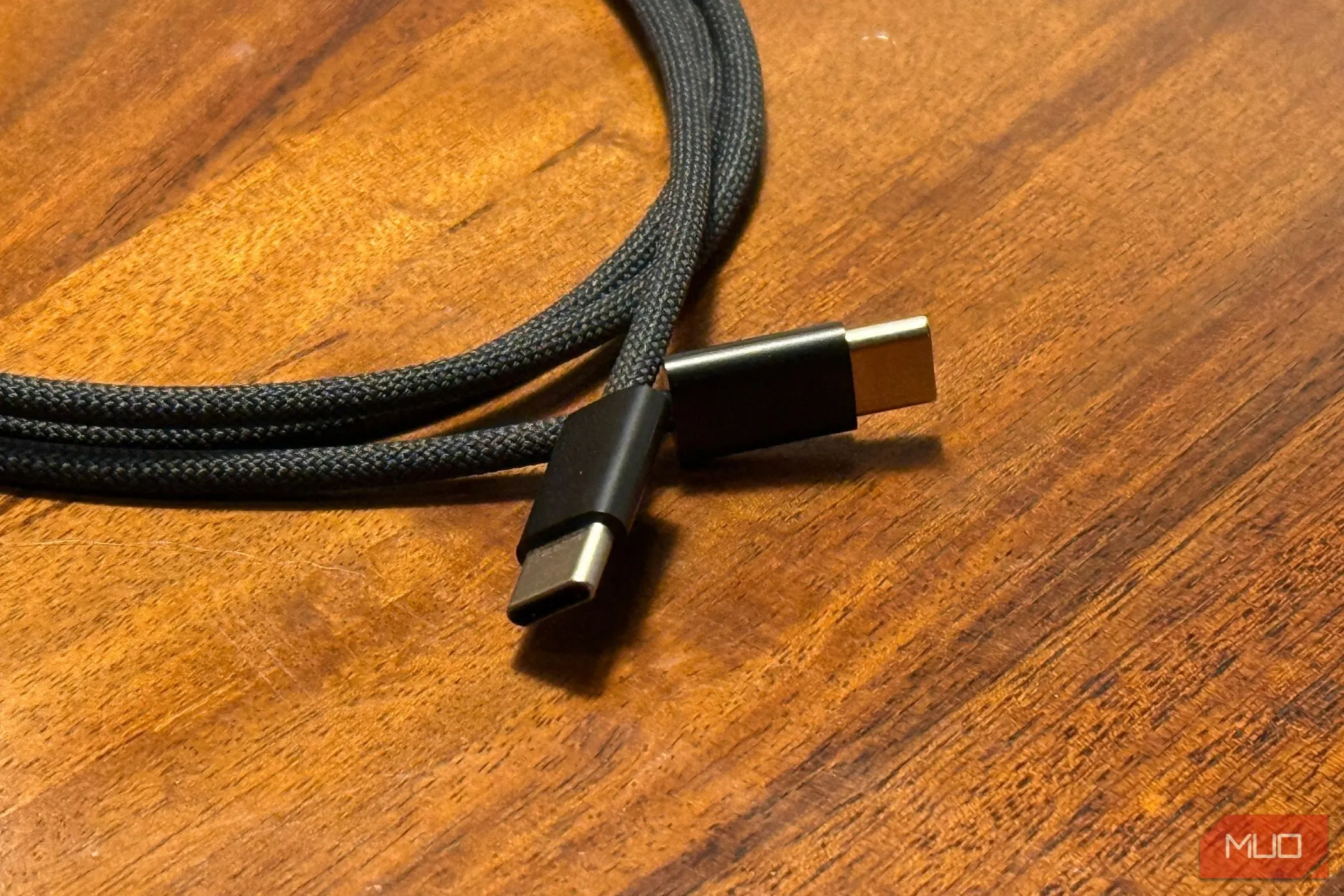 Hai đầu cáp USB-C sang USB-C màu trắng đặt trên mặt bàn gỗ, minh họa loại cáp sạc nhanh cho iPhone 15 trở lên.