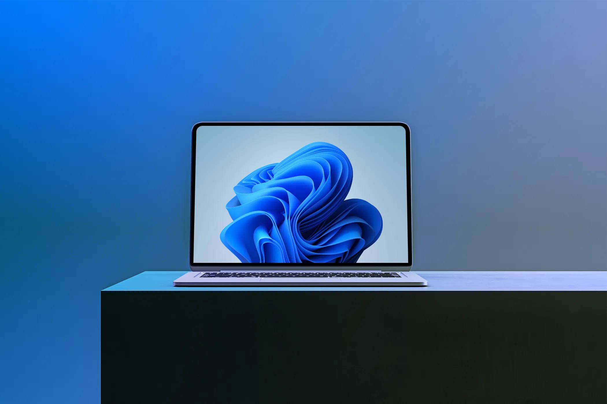 Hình ảnh laptop hiển thị màn hình nền Windows 11 trên bề mặt tối