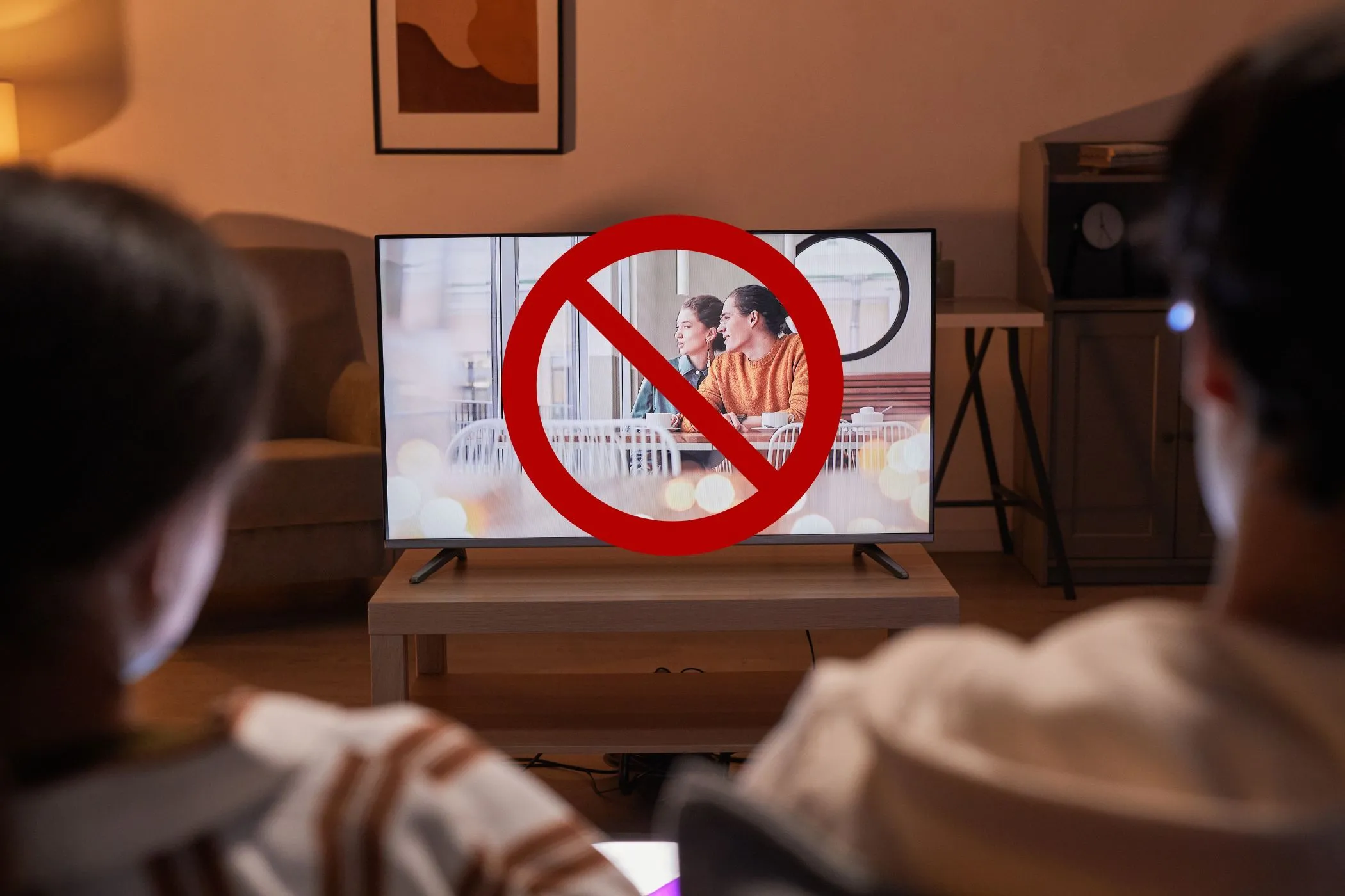 Hình ảnh mô tả việc một cặp đôi đang xem TV nhưng màn hình bị gạch chéo, biểu thị việc các ứng dụng đa phương tiện chạy nền có thể ảnh hưởng đến kết quả kiểm tra tốc độ internet do chia sẻ băng thông.