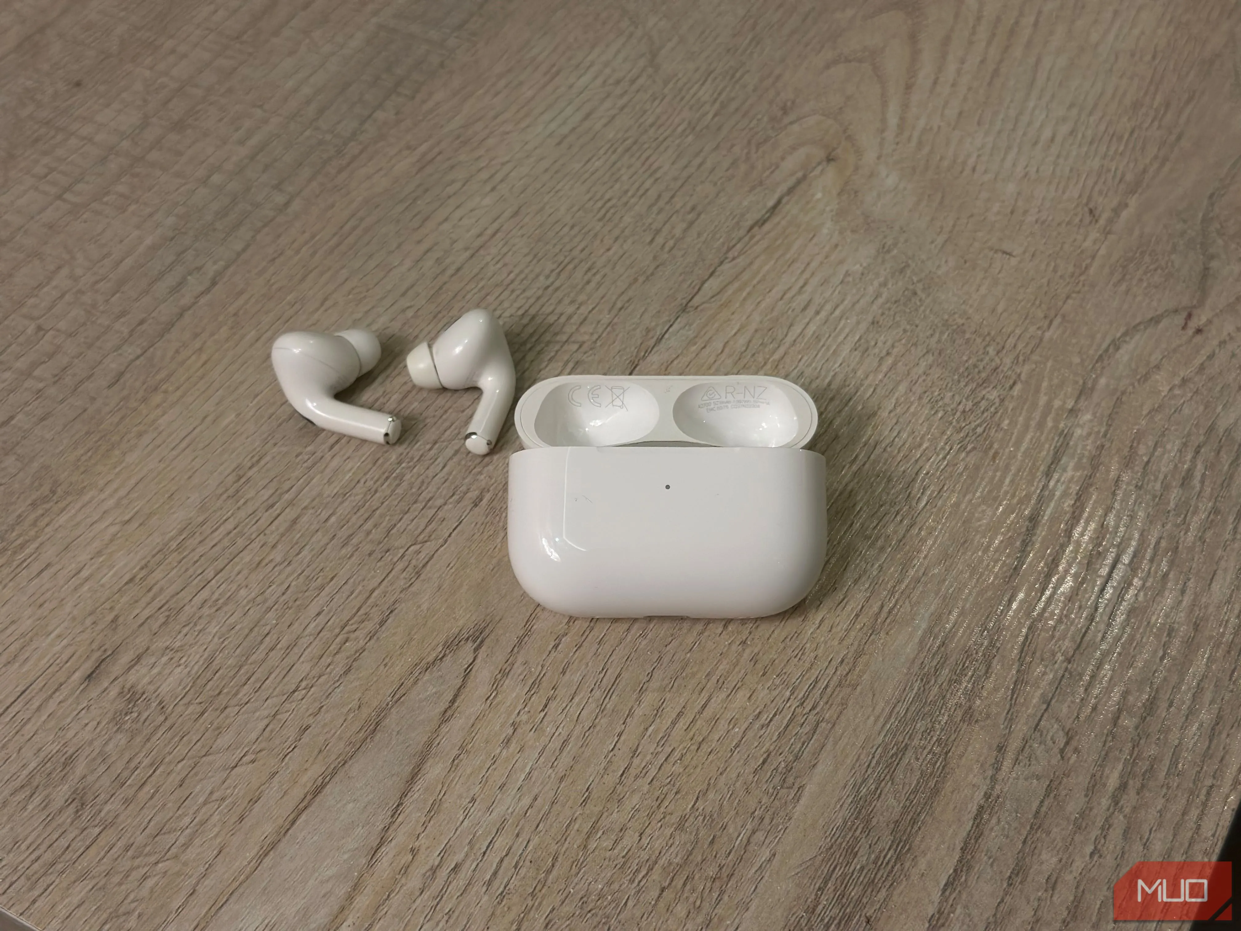 Hộp sạc AirPods mở nắp cùng tai nghe, minh họa vị trí số model và số serial được in bên trong nắp hộp sạc