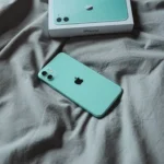 iPhone 11 màu xanh bạc hà nằm trên drap giường, thể hiện thiết kế cao cấp và độ bền