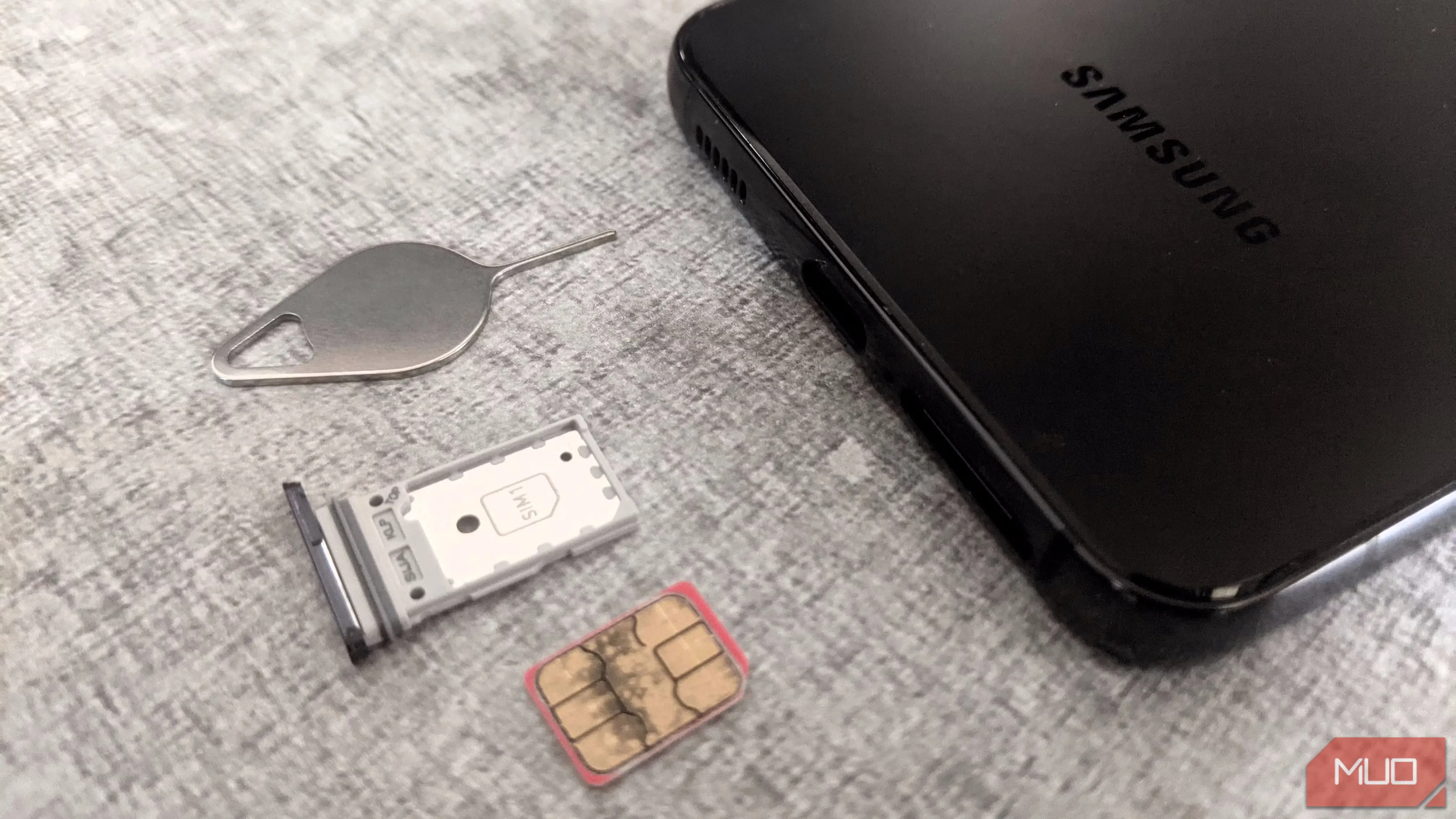 Khay SIM và điện thoại Samsung cùng công cụ lấy SIM, minh họa nguy cơ bị tấn công SIM-swapping để chiếm đoạt tài khoản.
