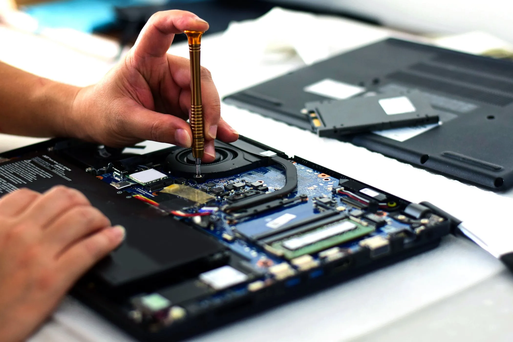 Kỹ thuật viên đang sửa chữa bo mạch chủ laptop, minh họa sự phức tạp khi thay thế linh kiện.