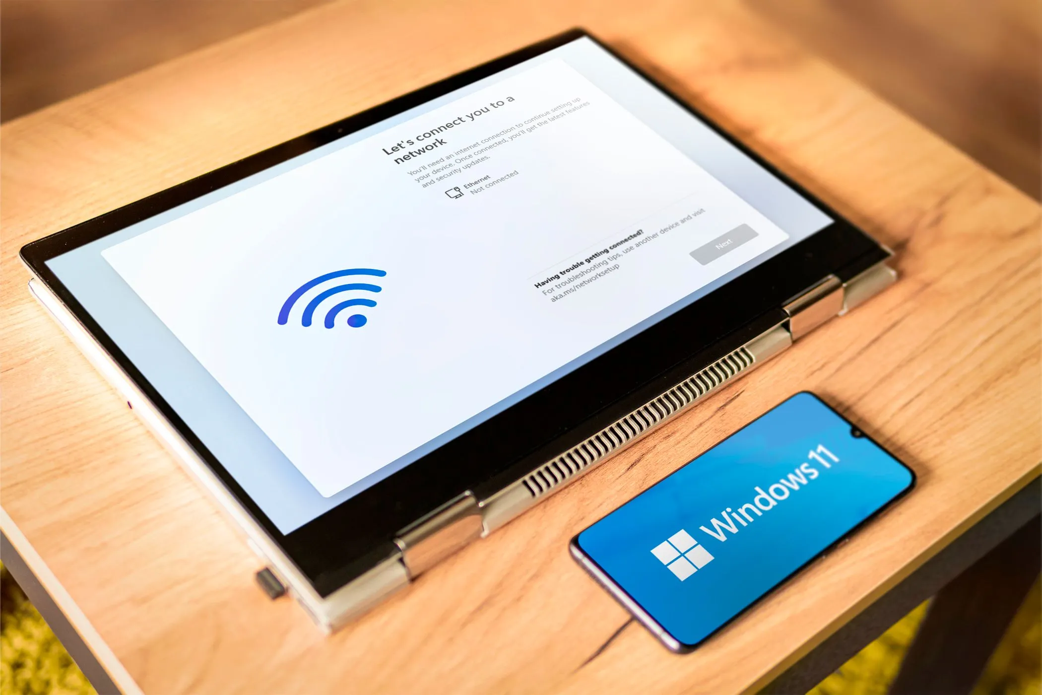 Laptop chạy Windows 11 cùng điện thoại Android hiển thị logo Windows, tượng trưng cho khả năng điều khiển máy tính từ xa bằng Android.