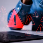 Laptop hiển thị cảnh báo vi phạm dữ liệu với biểu tượng tam giác đỏ, minh họa nguy cơ tấn công ransomware hoặc mất an toàn thông tin khi sử dụng các công cụ chuyển đổi file không đáng tin cậy.