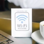 Laptop và biển báo Wi-Fi trong phòng khách sạn, minh họa nhu cầu kết nối Internet khi đi du lịch.