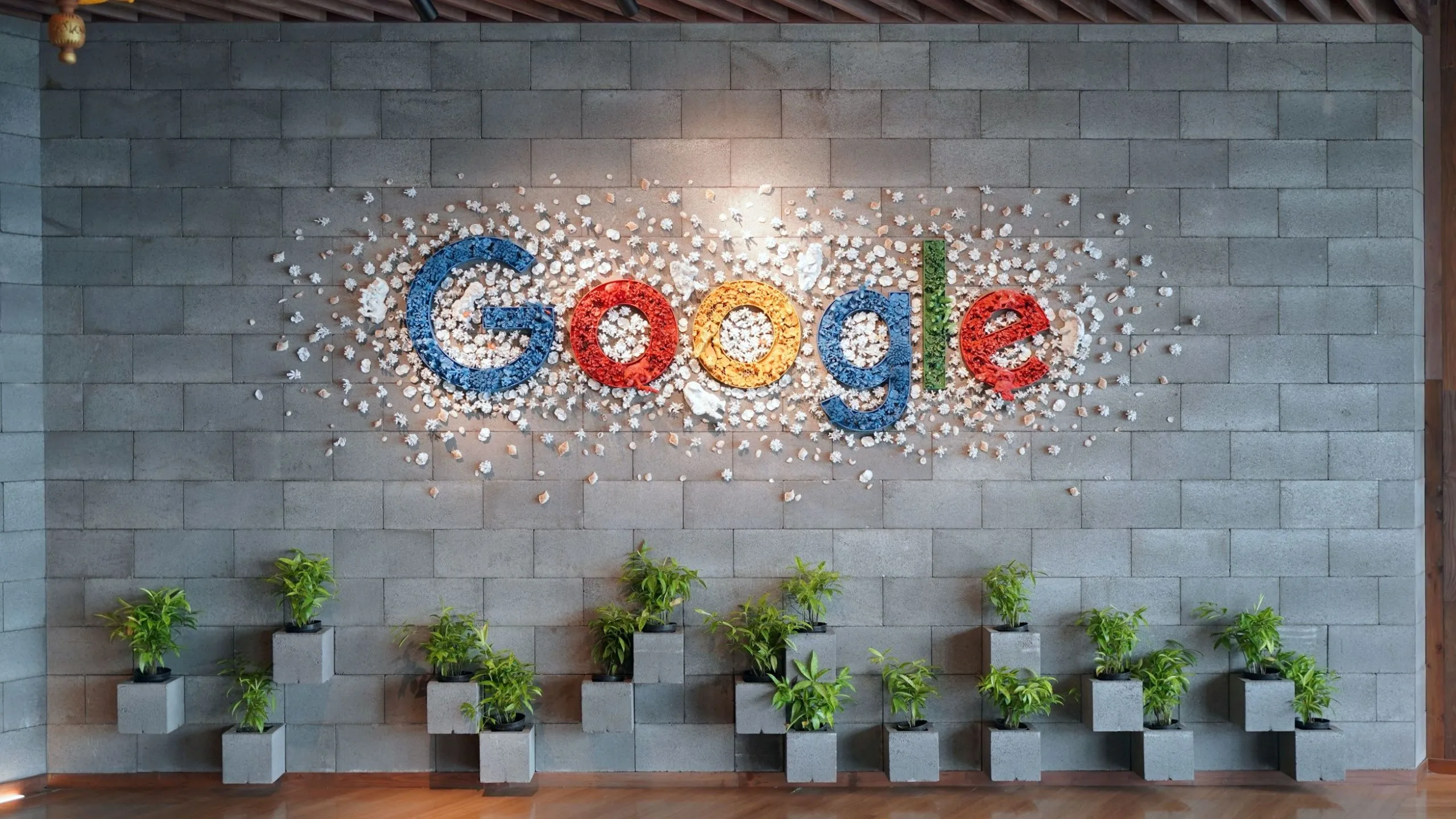 Logo Google trên tường văn phòng với cây xanh, biểu tượng cho sự đồng bộ hóa liền mạch của Chromebook với hệ sinh thái Google