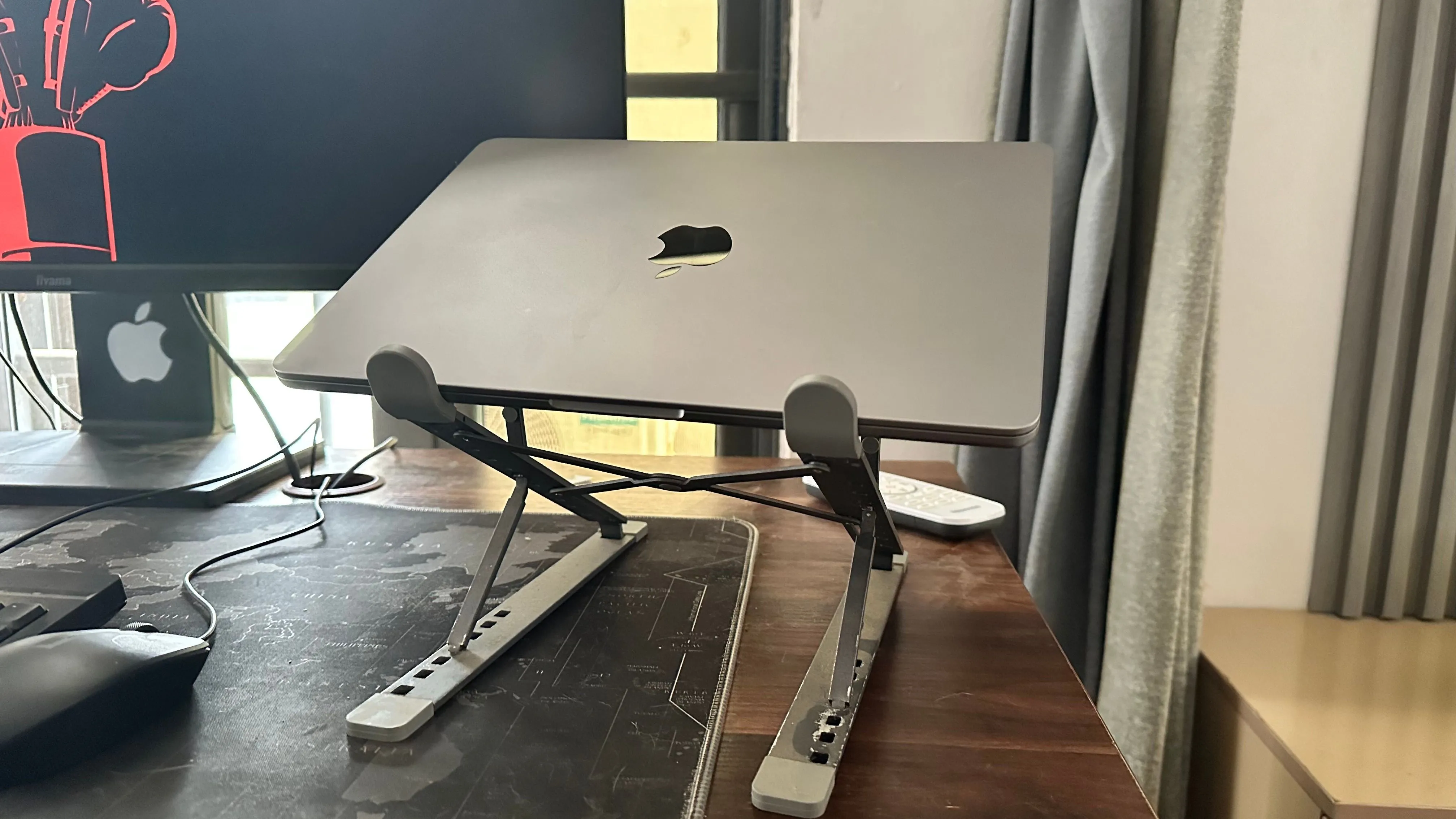 MacBook đặt trên đế tản nhiệt cạnh màn hình ngoài, minh họa cấu hình làm việc với màn hình phụ