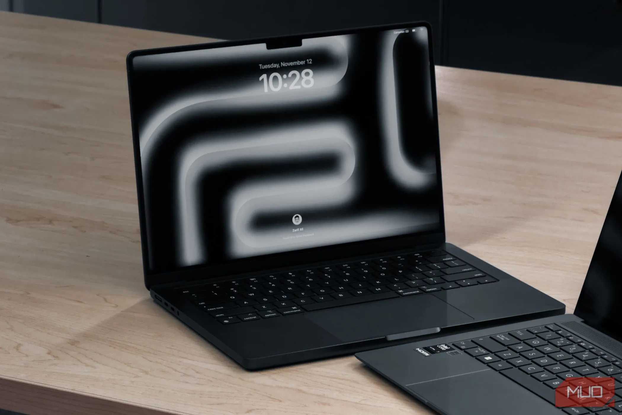 MacBook Pro M4 bên cạnh laptop khác trên bàn gỗ, minh họa thiết kế sang trọng và hiệu năng của laptop macOS.