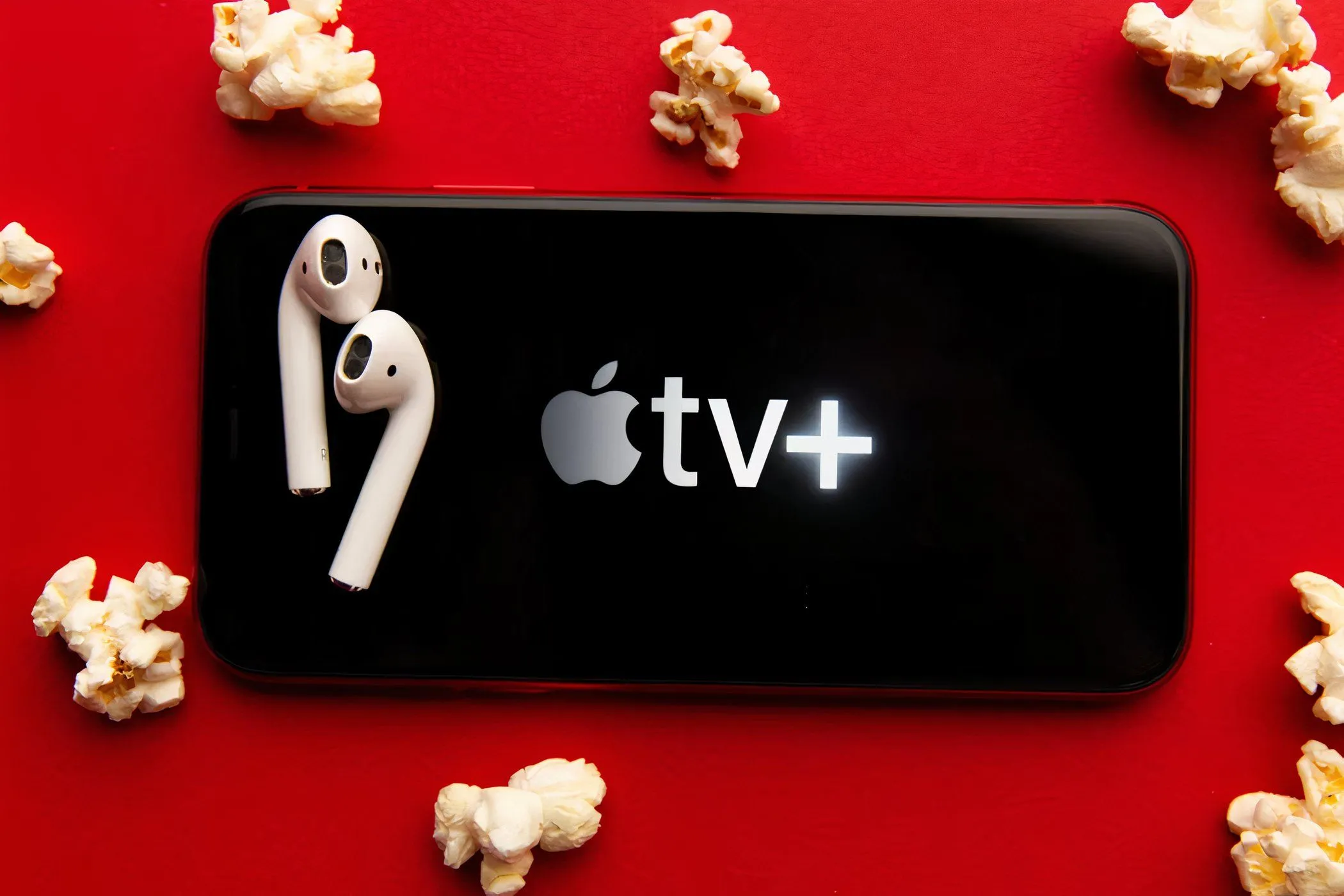 Màn hình điện thoại hiển thị ứng dụng Apple TV+ cùng bỏng ngô và tai nghe, tượng trưng cho trải nghiệm giải trí di động tiện lợi.