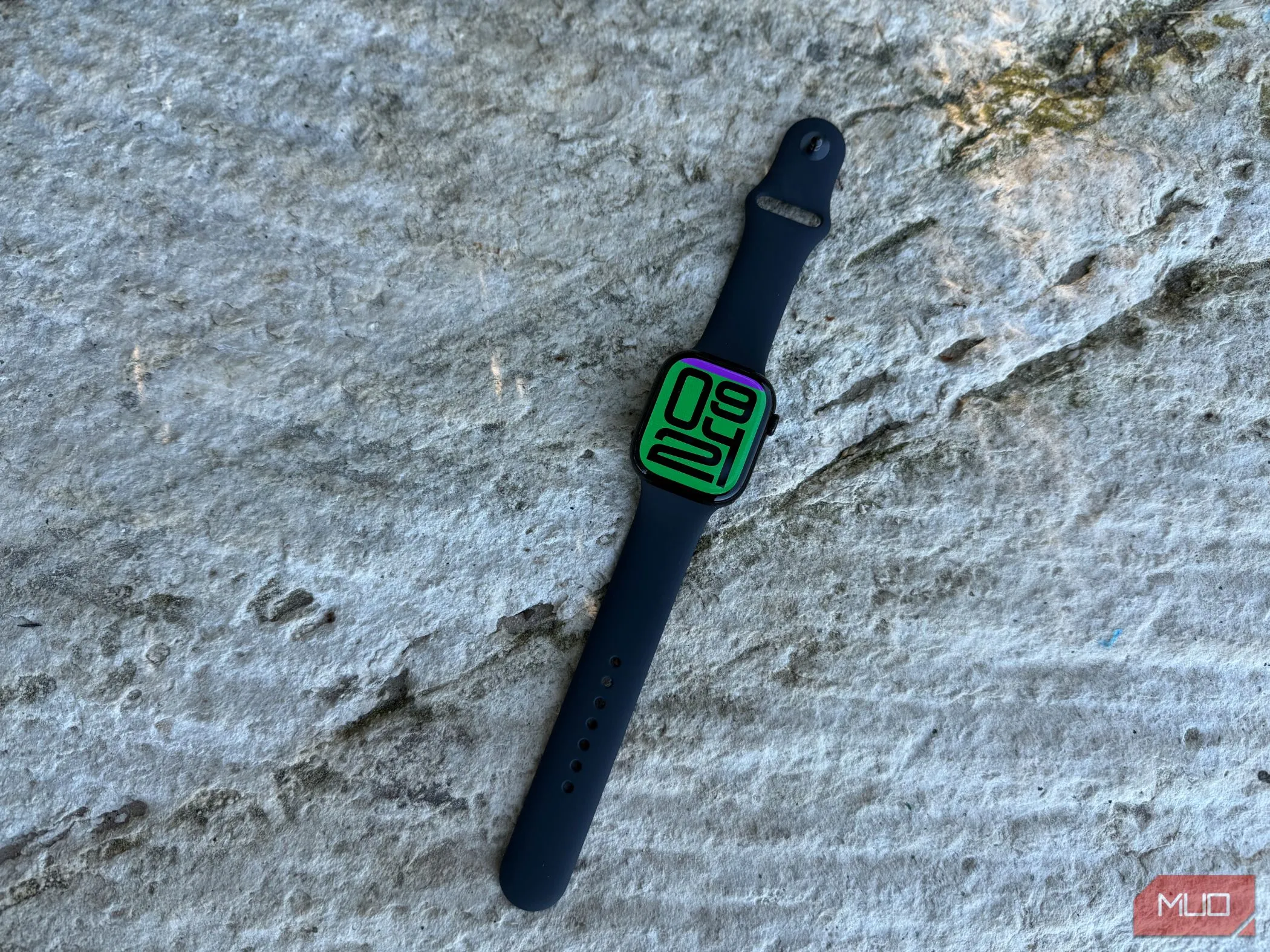 Mặt đồng hồ Apple Watch Series 10 hiển thị giao diện Flux màu sắc, với dây đeo xanh đậm, tôn lên thiết kế mỏng nhẹ.