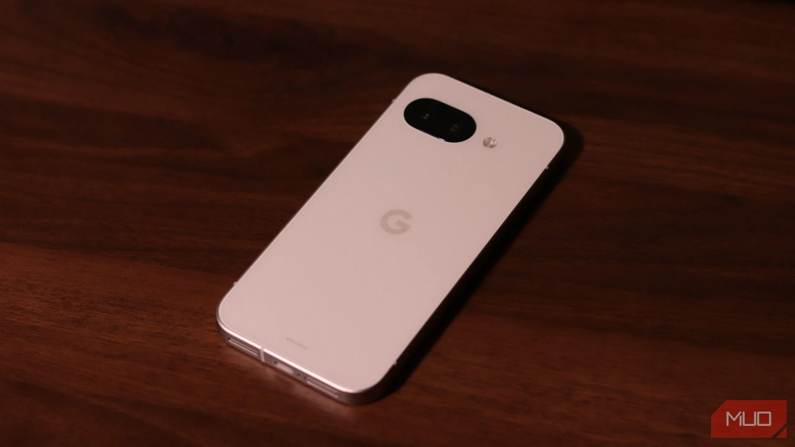 Mặt lưng và cụm camera sau của điện thoại Pixel 9a đặt trên bề mặt gỗ