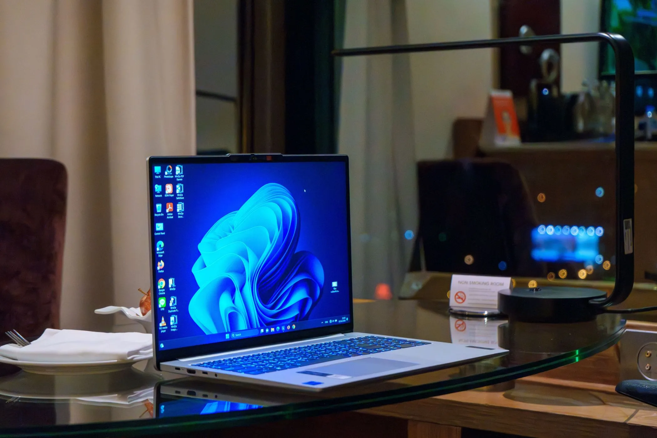 Máy tính xách tay Windows đặt trên bàn kính, hiển thị giao diện màn hình desktop với các biểu tượng, minh họa vị trí xuất hiện dấu chìm Windows 11.