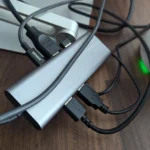 Một dock USB-C truyền thống với nhiều cáp kết nối lộn xộn, thể hiện vấn đề về sự gọn gàng trên bàn làm việc.