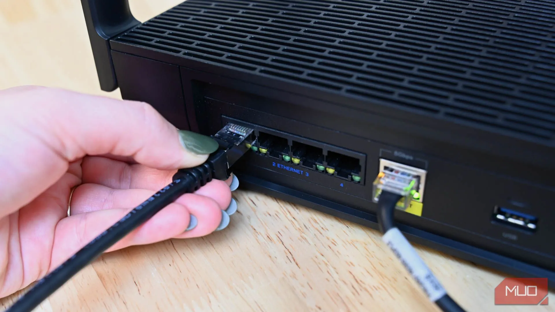 Một người đang cắm cáp Ethernet vào bộ định tuyến, minh họa cho việc sử dụng kết nối mạng có dây.
