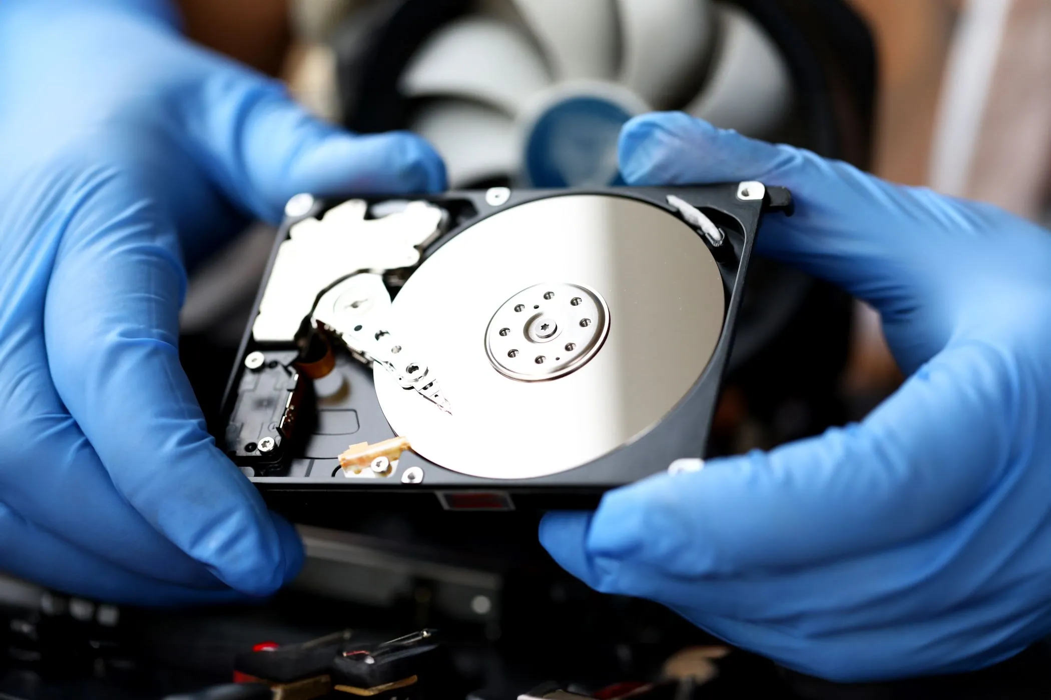 Một người đang cầm ổ cứng HDD với đĩa quay bên trong, minh họa vấn đề dung lượng lưu trữ hạn chế của Chromebook.