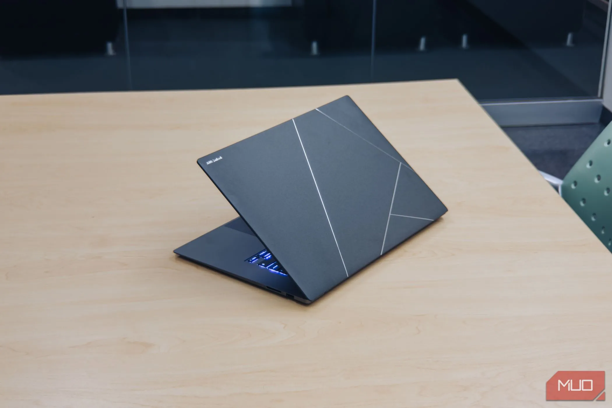 Nắp lưng Ceraluminum của ASUS Zenbook S 16 trên mặt bàn gỗ