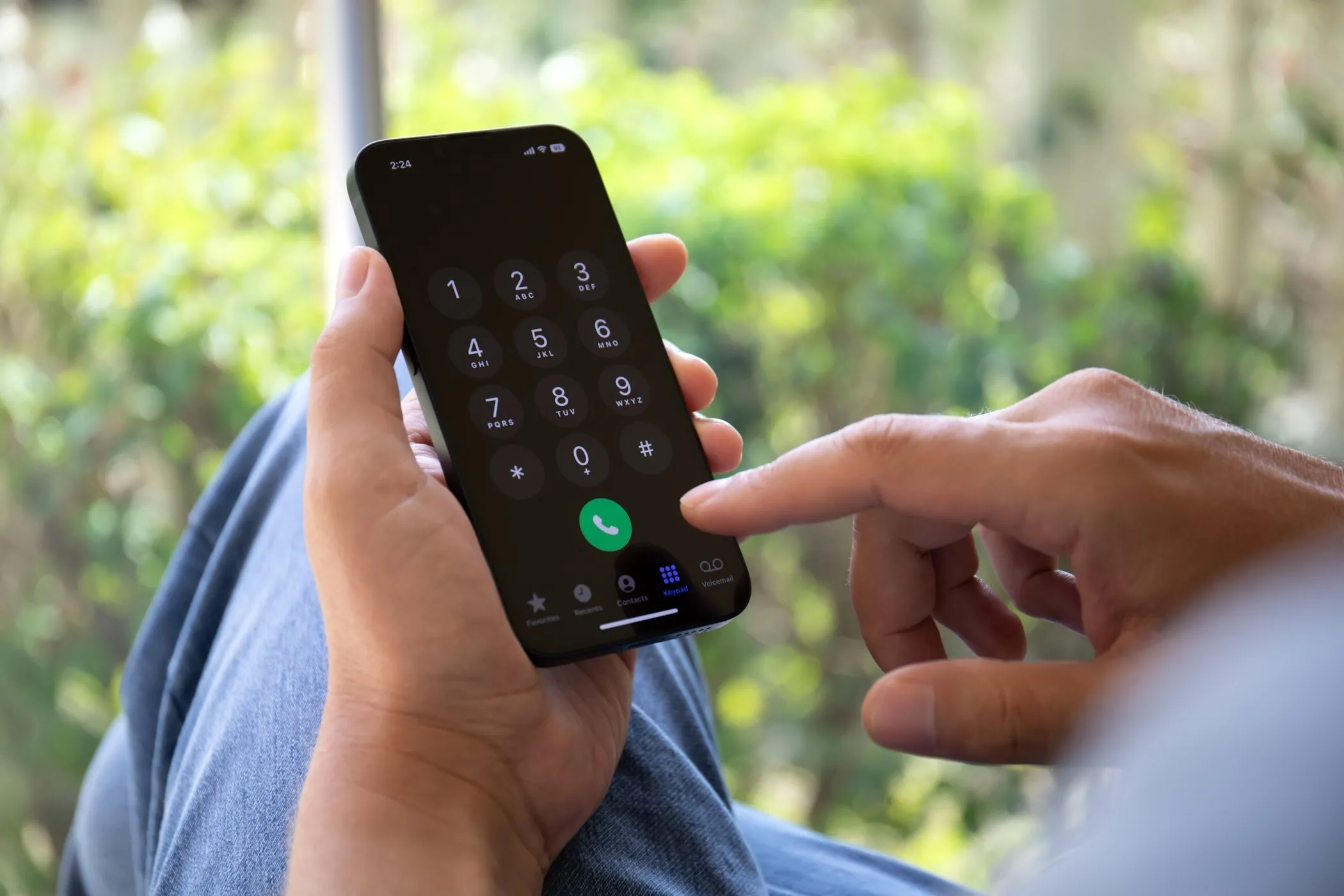 Người đàn ông đang cố gắng nhập số điện thoại trên iPhone, thể hiện sự phụ thuộc của 2FA SMS vào tín hiệu di động.