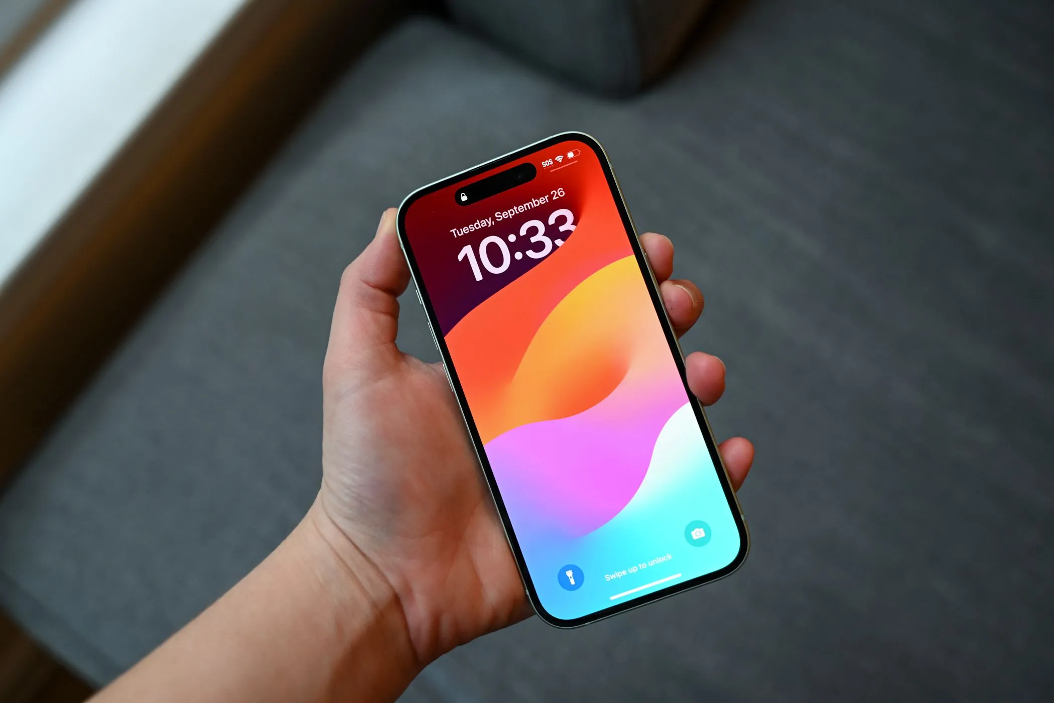 Người dùng đang cầm iPhone 15 ở màn hình khóa