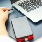 Người phụ nữ cắm cáp USB-C vào laptop và sạc dự phòng