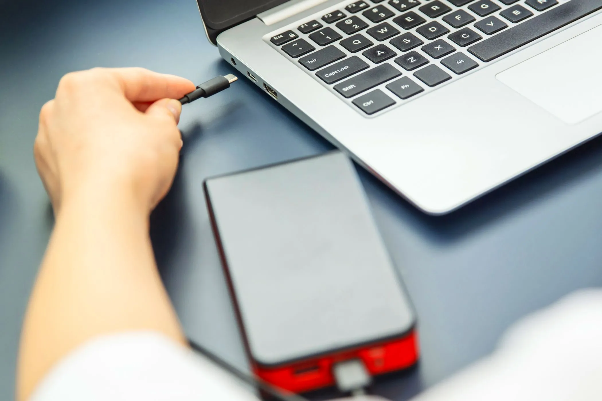 Người phụ nữ cắm cáp USB-C vào laptop và sạc dự phòng