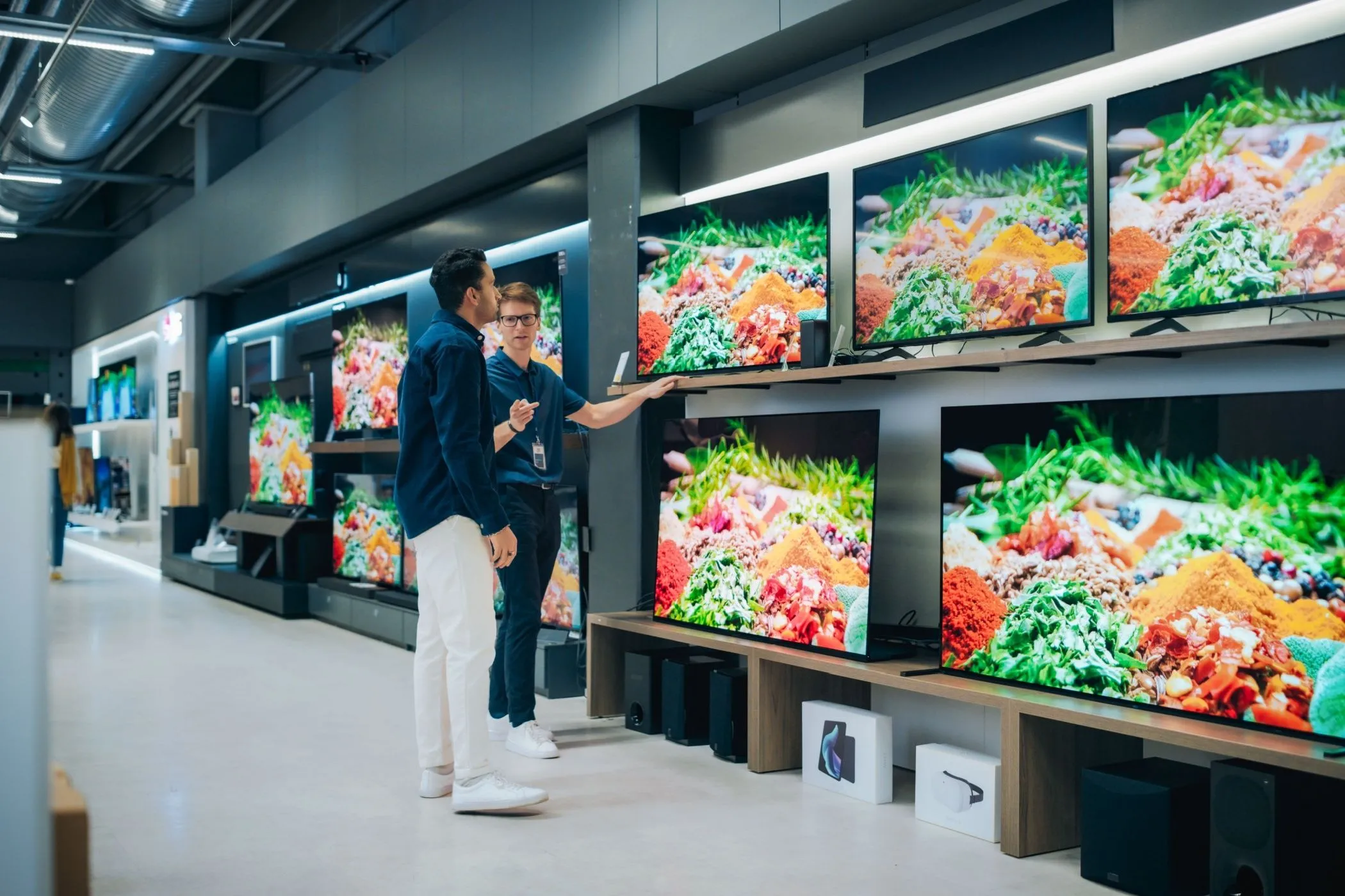 Nhân viên cửa hàng tư vấn TV cho khách hàng, minh họa cho trải nghiệm mua sắm cá nhân hóa và ưu đãi dành cho khách thân thiết