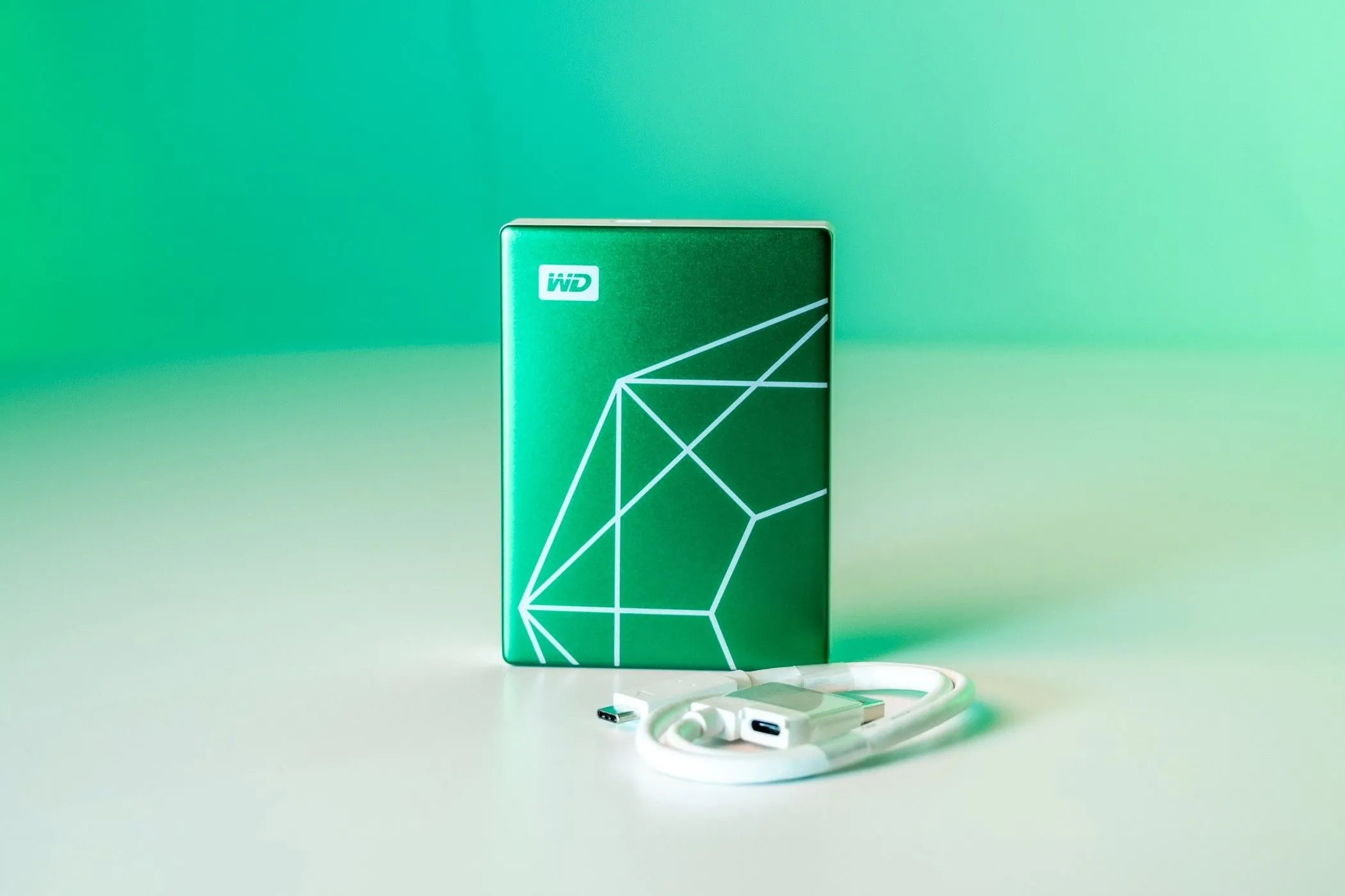 Ổ cứng WD My Passport Ultra Emerald Edition với cáp USB-C đi kèm, làm nổi bật lớp vỏ kim loại màu xanh ngọc lục bảo và cổng kết nối