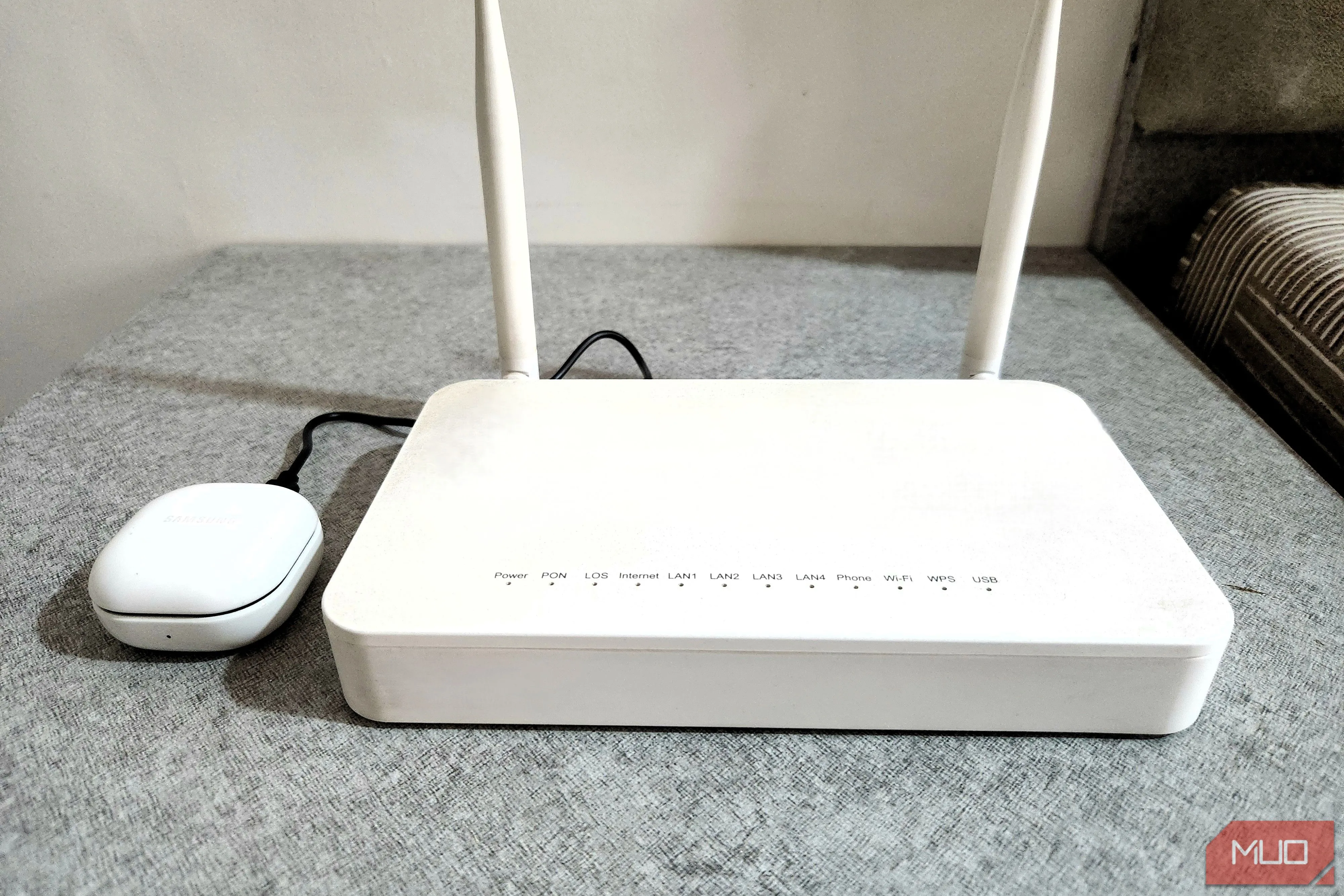 Tai nghe Bluetooth đang được sạc qua cổng USB của router, tiện lợi cho các thiết bị nhỏ.