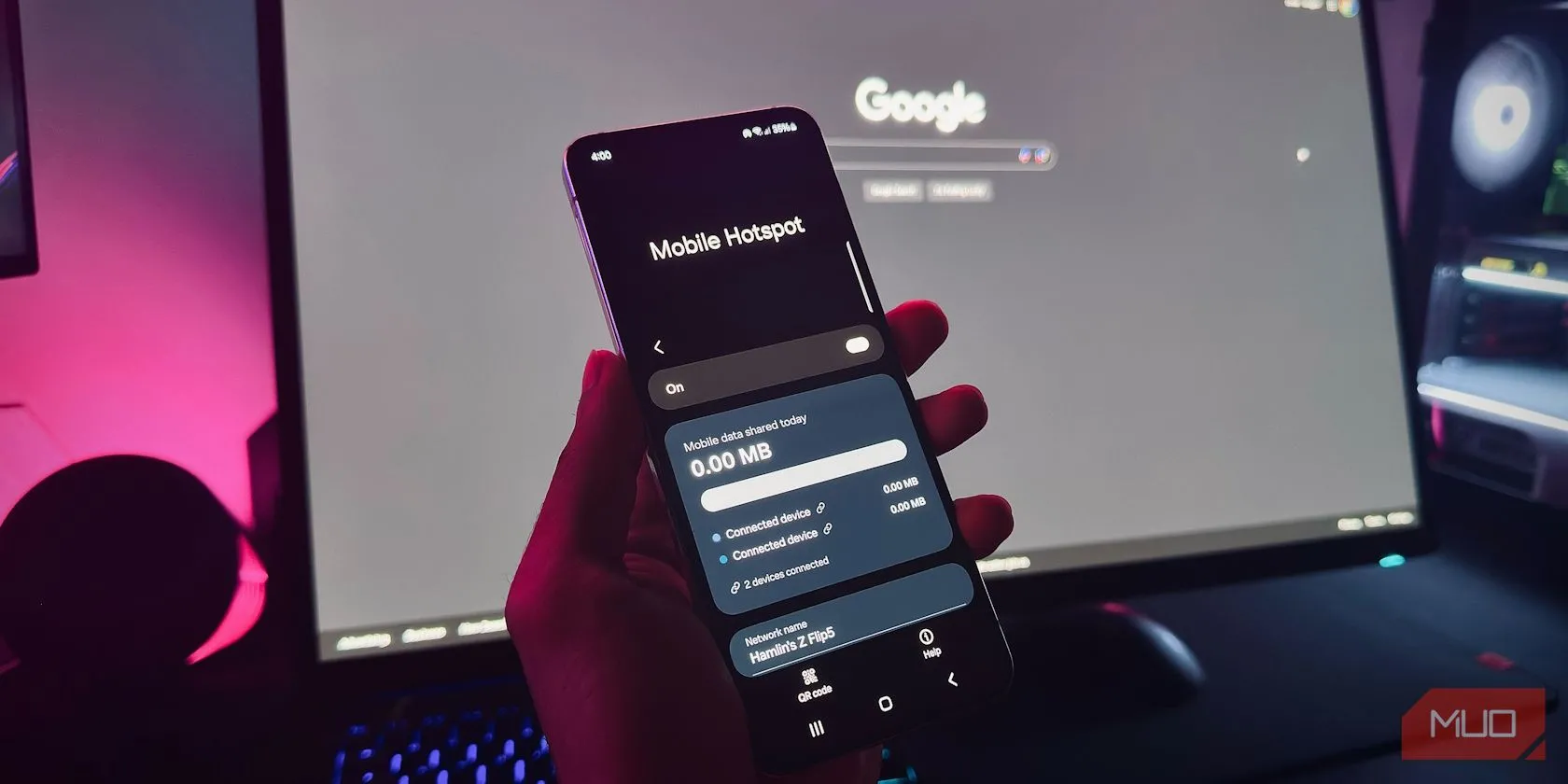 Tay cầm điện thoại Android hiển thị tùy chọn Điểm truy cập di động (Mobile Hotspot) trước màn hình máy tính.