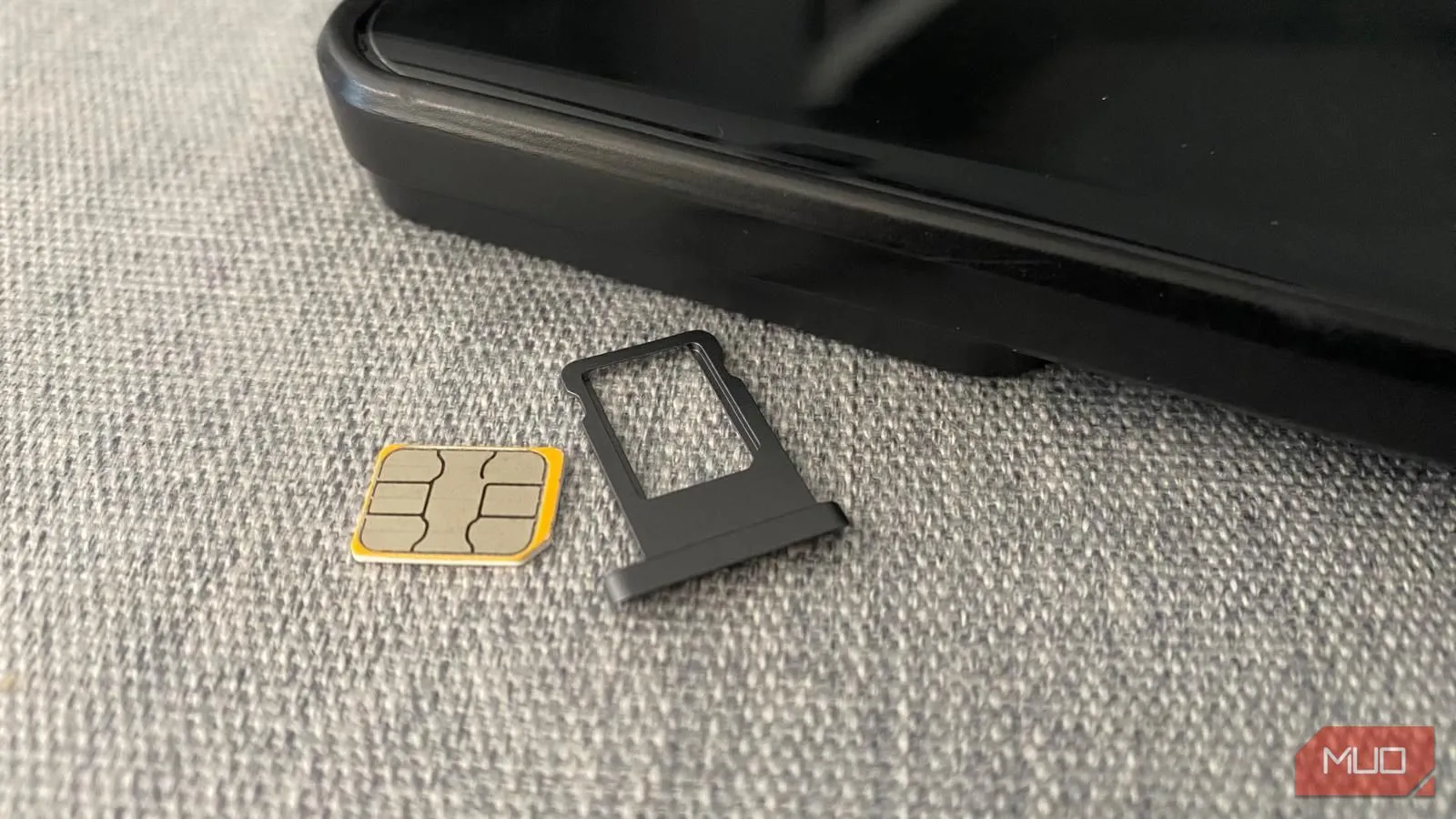 Thẻ SIM vật lý và khay đựng đặt cạnh điện thoại, minh họa sự phổ biến và quen thuộc của loại SIM này.